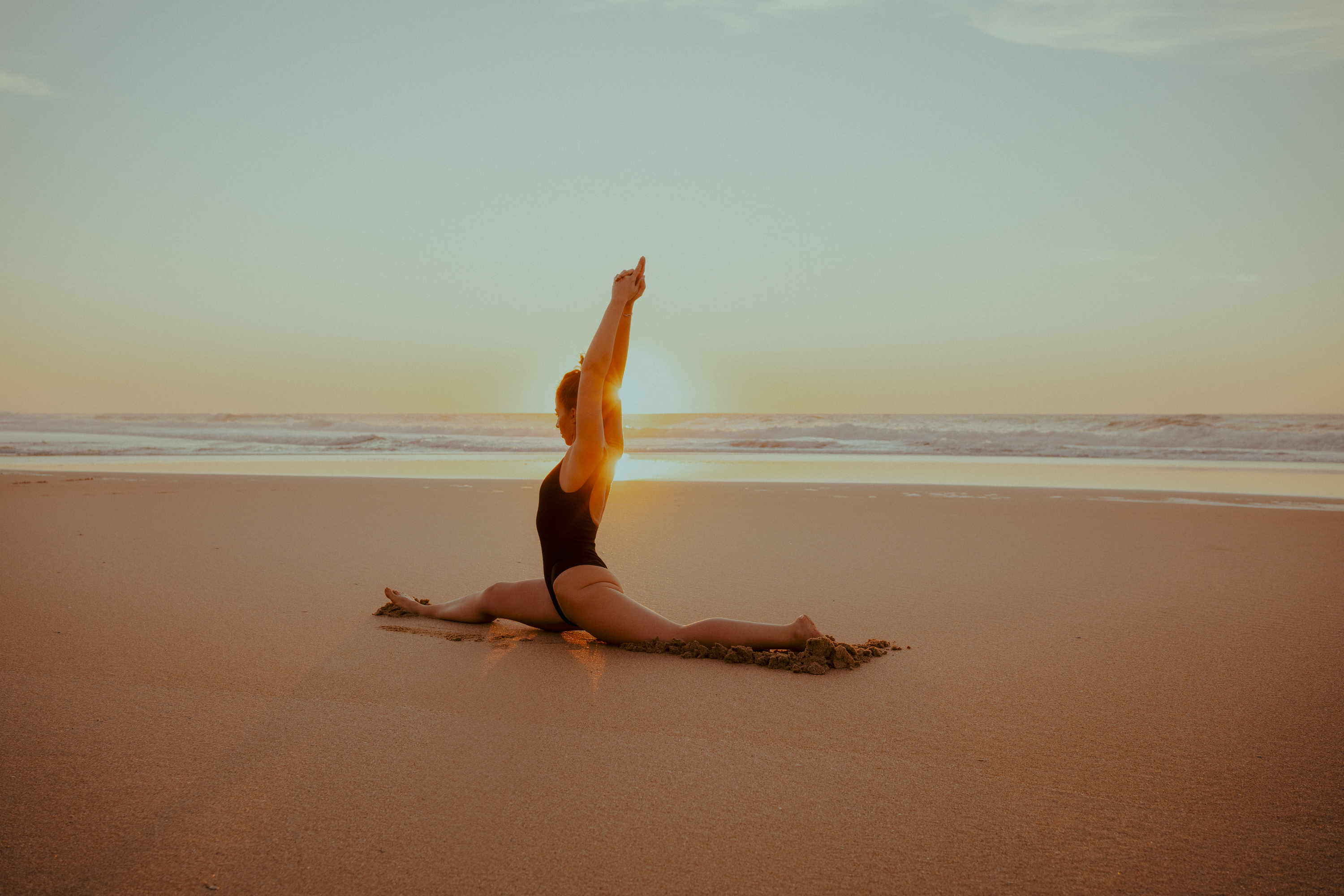 Anna Sadova practicing yoga on the beach at sunset